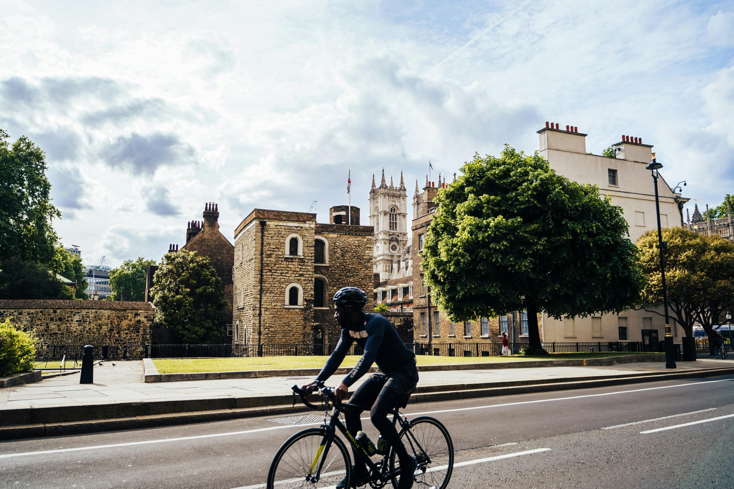Rowerzysta przejeżdża obok historycznych budynków w słoneczny dzień w Londynie, niedaleko Opactwa Westminsterskiego.
