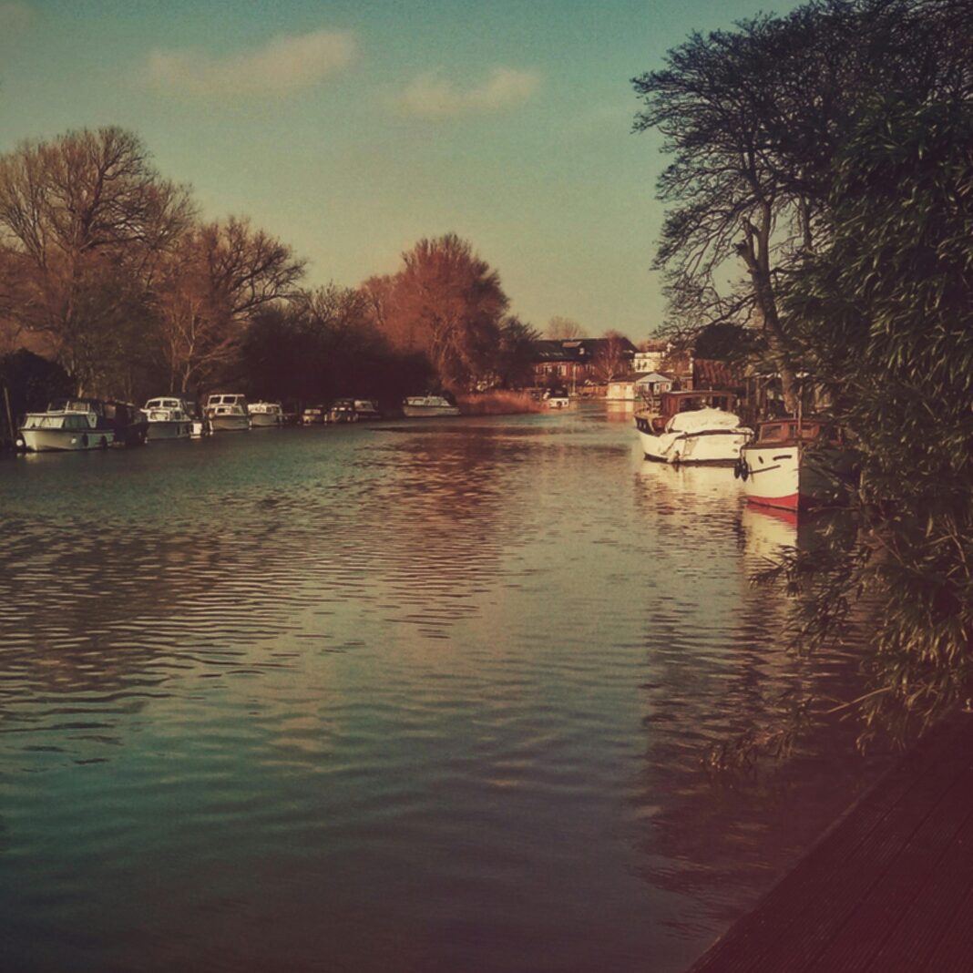 Spokojny widok na rzekę z łodziami i drzewami w Beccles w Wielkiej Brytanii.