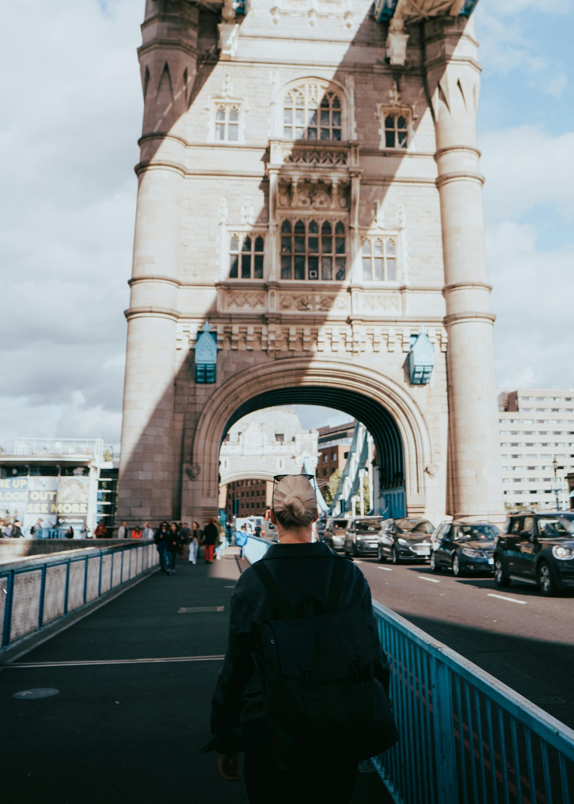 Widok z tyłu osoby na Tower Bridge w Londynie, przedstawiający życie miejskie i kultową architekturę.