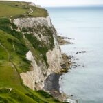 Odkryj kultowe Białe Klify Dover z widokiem na kanał La Manche w pogodny, pochmurny dzień.