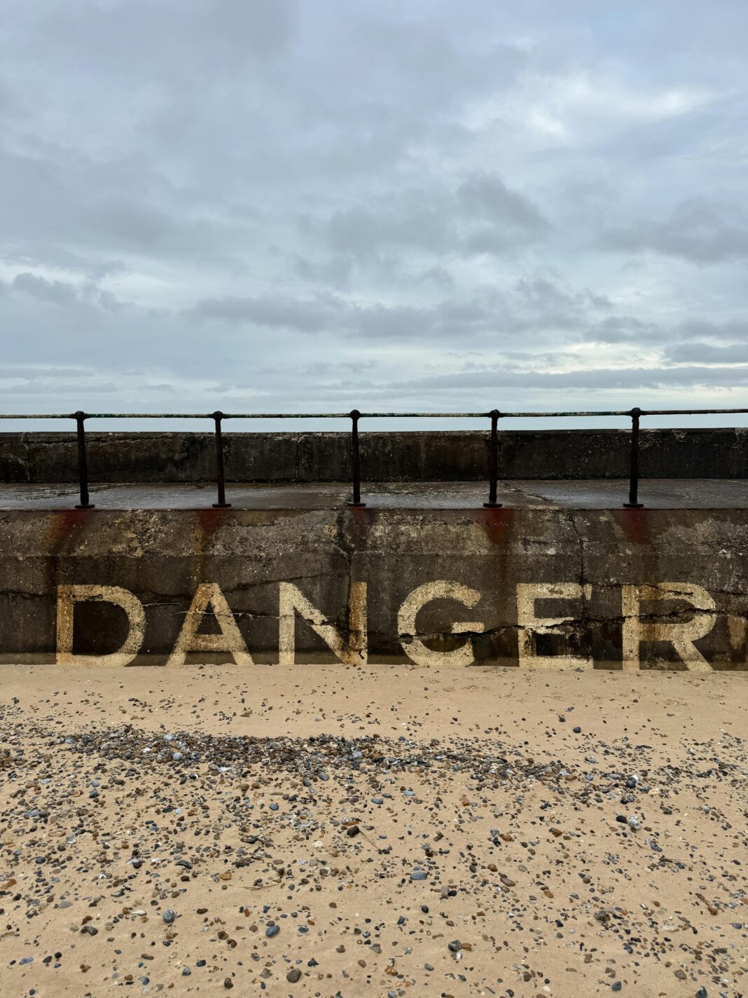 anglia Znak ostrzegawczy na ścianie przybrzeżnej w Gorleston-on-Sea w Anglii, przedstawiający „NIEBEZPIECZEŃSTWO” w pochmurny dzień.