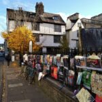 Urocza ulica Cambridge z jesiennymi liśćmi i żywymi plakatami w słoneczny dzień.
