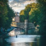 Katedra w Gloucester: Wędrówka przez Czas, Film i Legendę Spokojny widok na rzekę w Leicester w Wielkiej Brytanii, z zabytkowym mostem pod zachodzącym niebem.