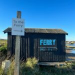 Urocza szopa i prom w Walberswick w Anglii, pod czystym, błękitnym niebem.