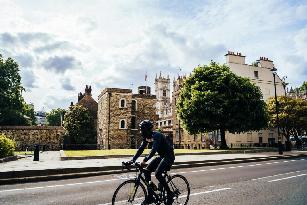 Rowerzysta przejeżdża obok historycznych budynków w słoneczny dzień w Londynie, niedaleko Opactwa Westminsterskiego.