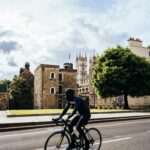 Rowerzysta przejeżdża obok historycznych budynków w słoneczny dzień w Londynie, niedaleko Opactwa Westminsterskiego.