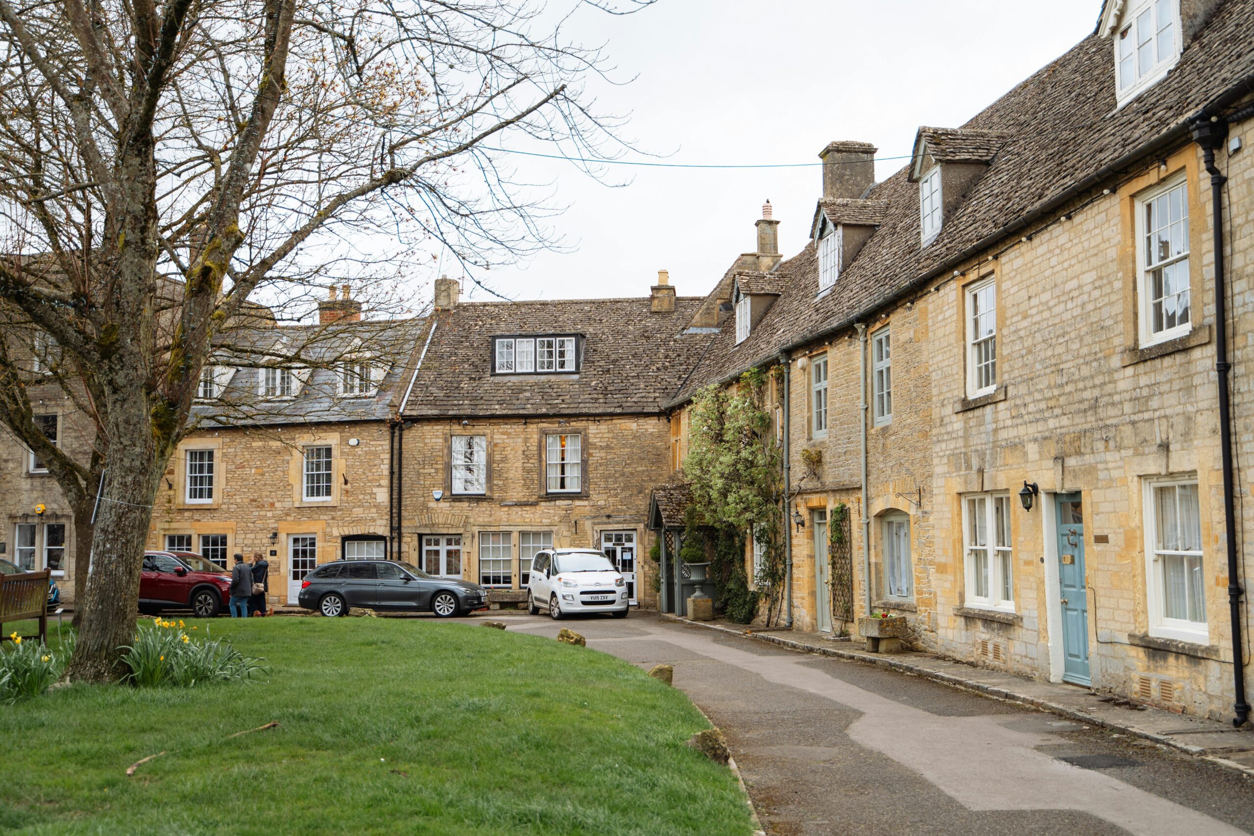 Malownicza ulica w tradycyjnej angielskiej wiosce z historycznymi kamiennymi domami w Cotswold i spokojną atmosferą.