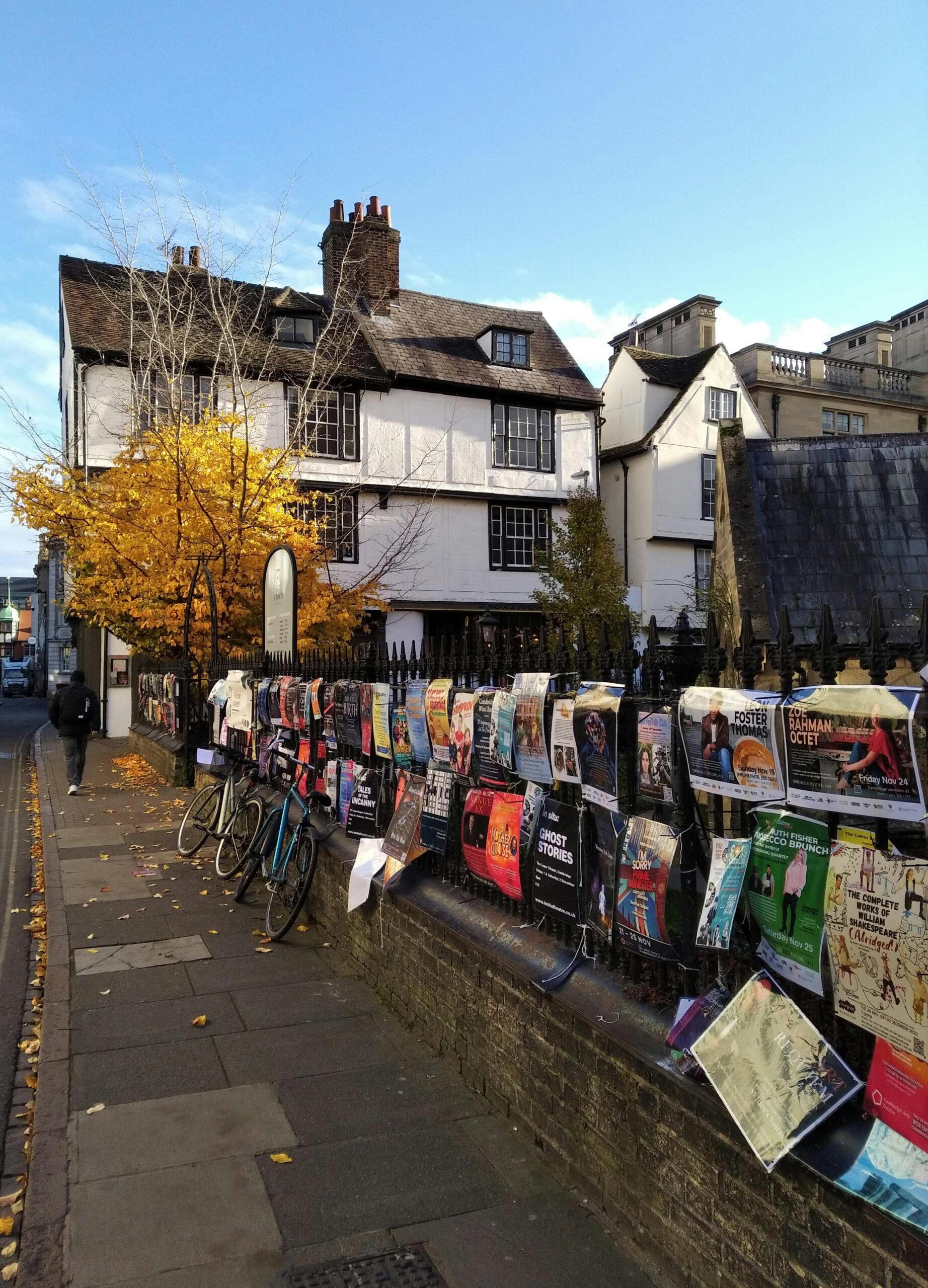 Urocza ulica Cambridge z jesiennymi liśćmi i żywymi plakatami w słoneczny dzień.