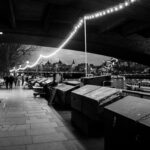 Czarno-białe zdjęcie promenady nad Tamizą w Londynie z wieczornymi światłami i panoramą miasta.