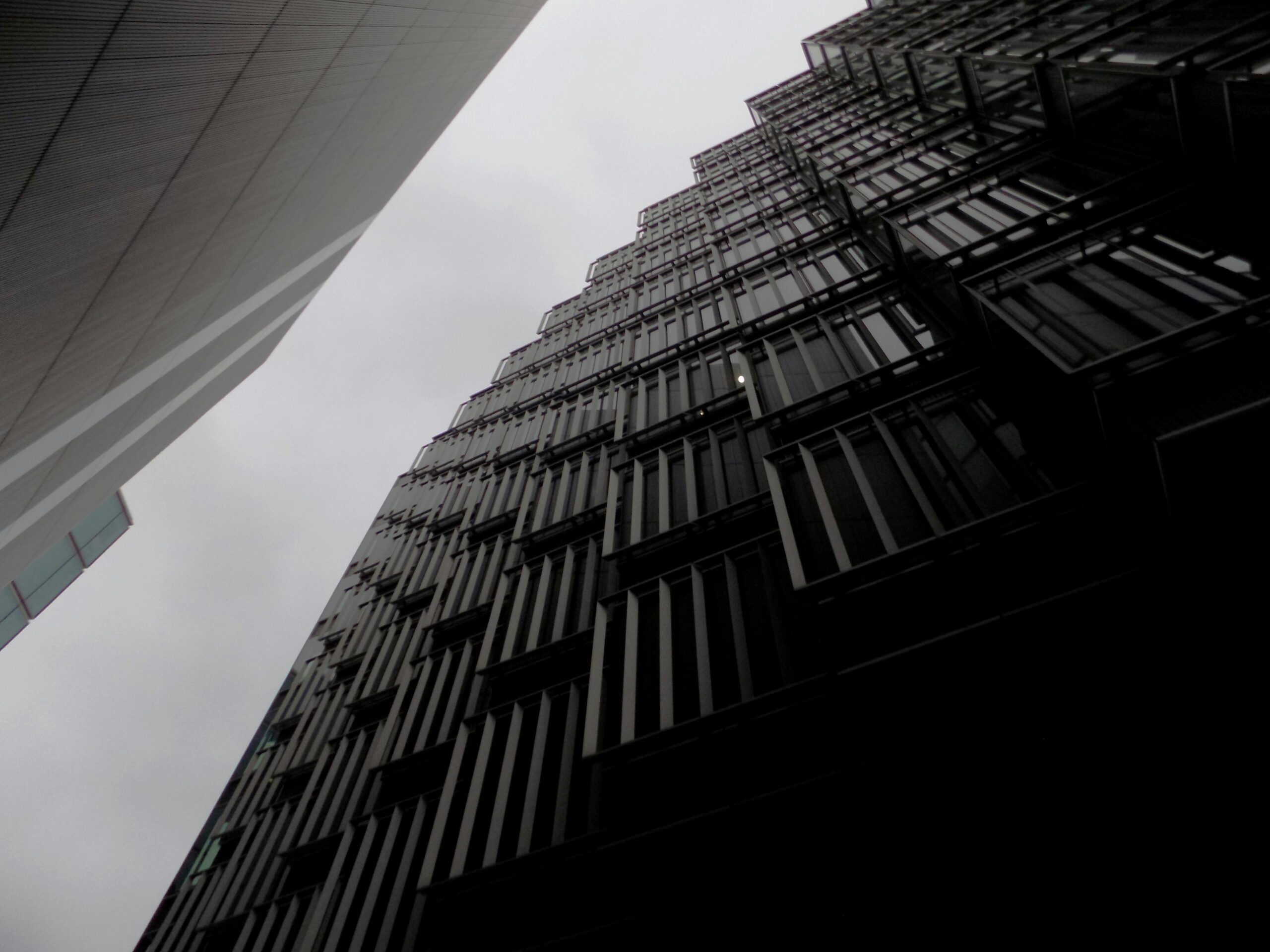 Dramatyczna perspektywa nowoczesnych drapaczy chmur na tle pochmurnego nieba w Londynie.