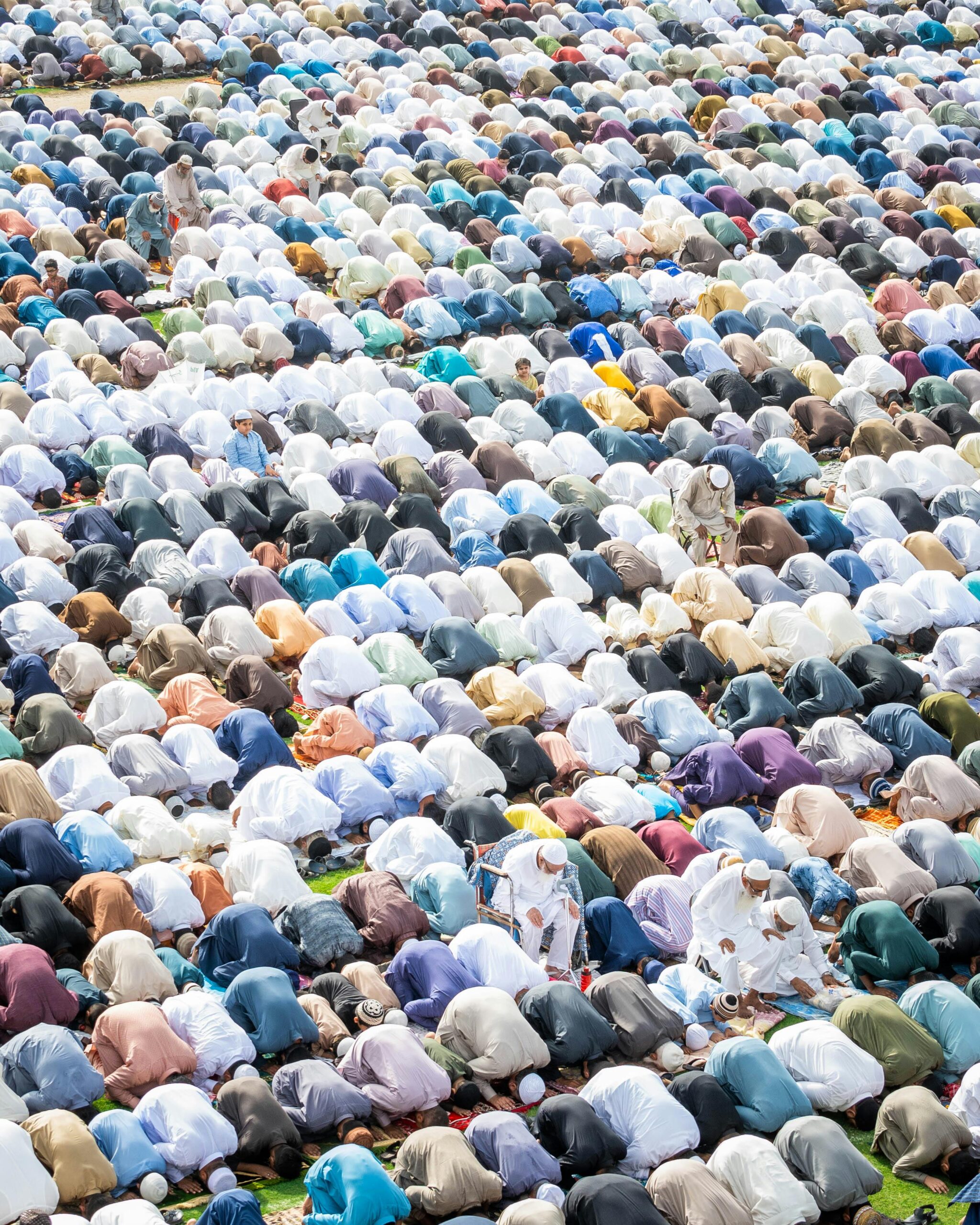 Ujęcie pod dużym kątem dużej grupy muzułmanów modlących się na zewnątrz, ukazujące islamski kult i jedność.