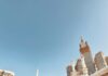 Duży tłum pielgrzymów w Masjid al-Haram w Mekce z widoczną wieżą zegarową Kaaba i Abraj Al Bait.