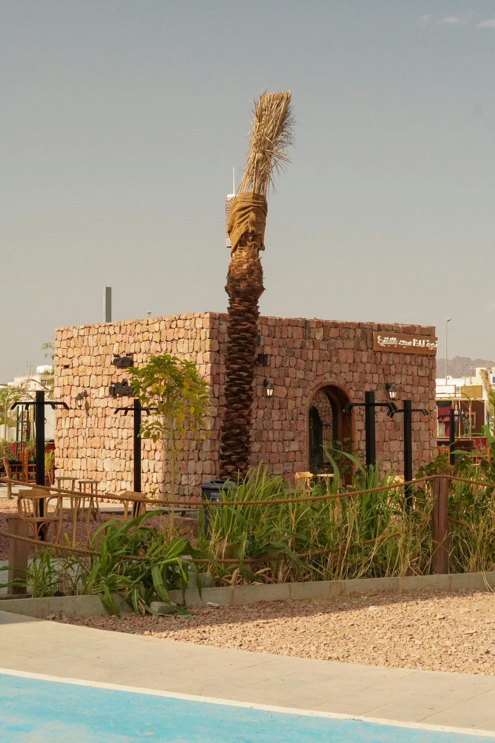 Rustykalny kamienny budynek z palmą w Medine w Arabii Saudyjskiej, prezentujący lokalną architekturę.