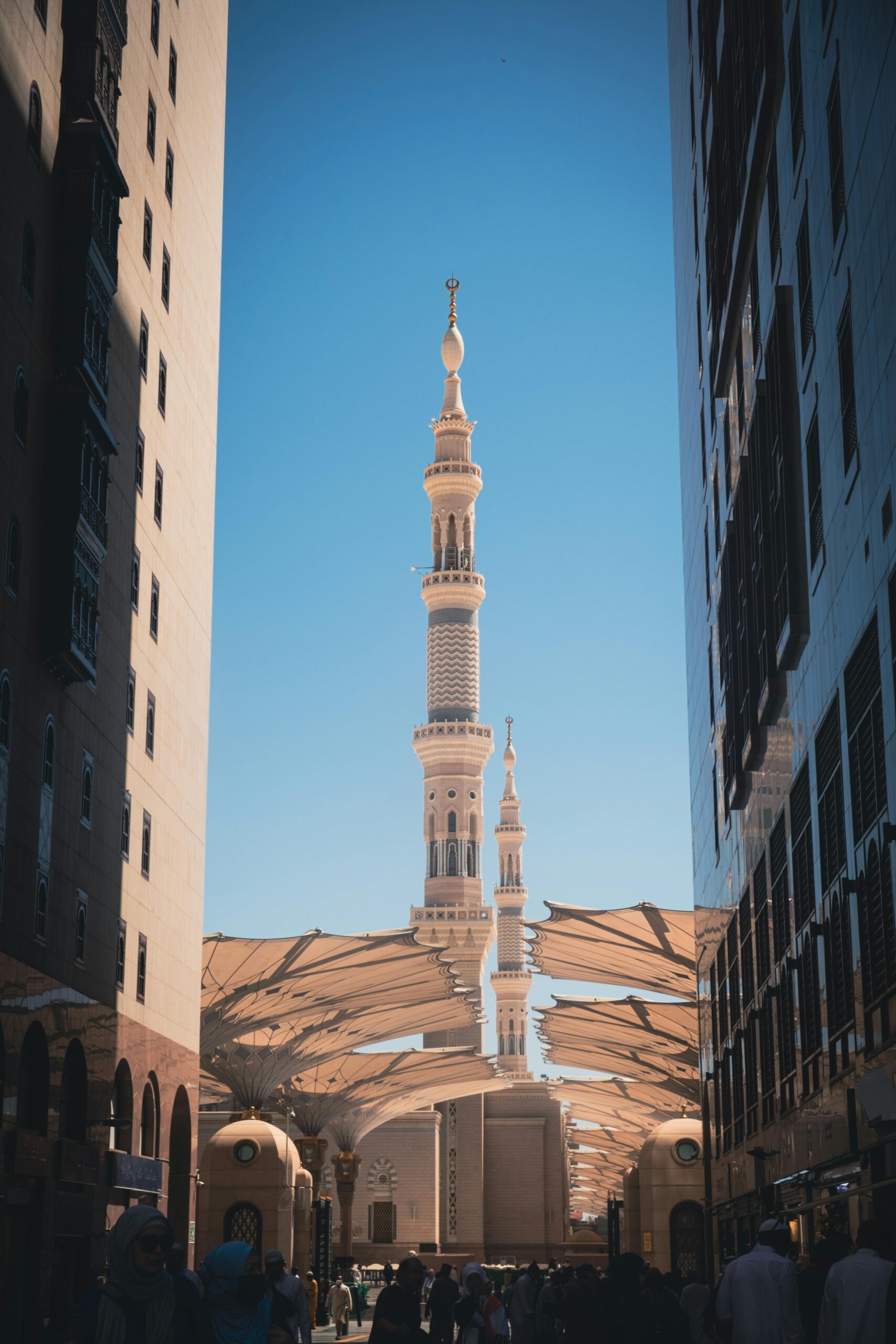 Meczet Proroka i jego kultowe minarety widziane pomiędzy dwoma budynkami w Medynie w Arabii Saudyjskiej.