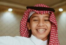 Uśmiechnięty arabski nastolatek ubrany w tradycyjny strój, prezentujący dziedzictwo kulturowe.