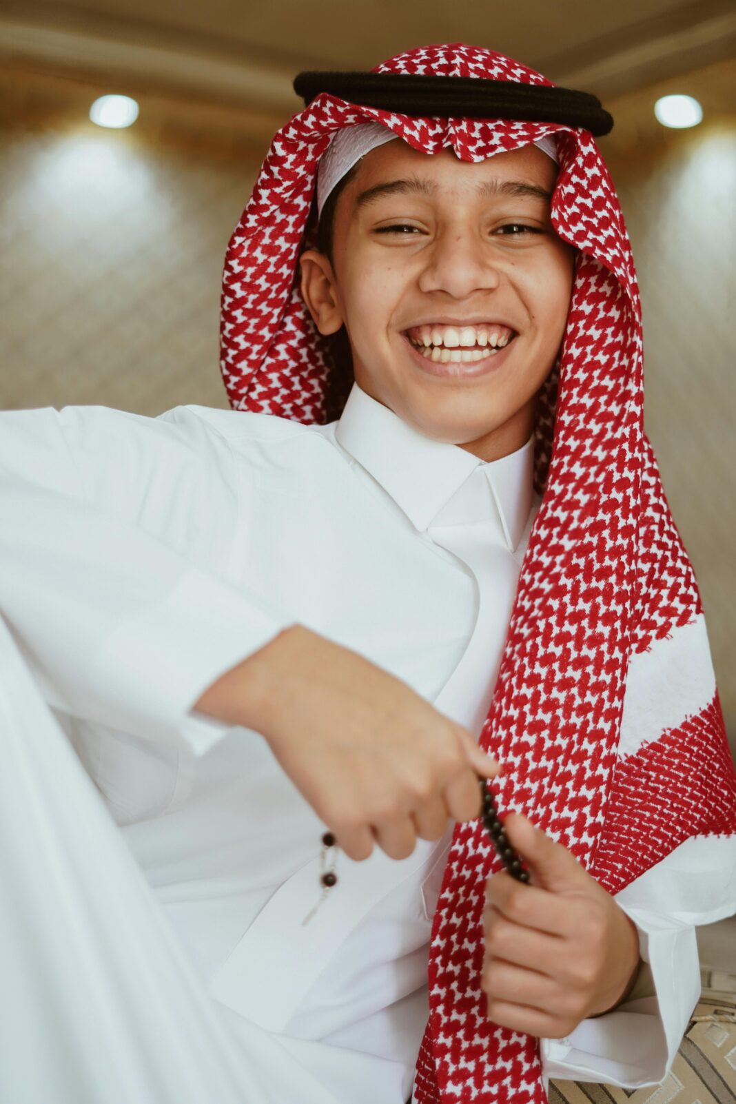 arabia-saudyjska Uśmiechnięty arabski nastolatek ubrany w tradycyjny strój, prezentujący dziedzictwo kulturowe.