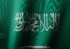 Szczegółowe zbliżenie flagi Arabii Saudyjskiej z eleganckim pismem arabskim i żywym zielonym kolorem.