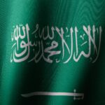 Szczegółowe zbliżenie flagi Arabii Saudyjskiej z eleganckim pismem arabskim i żywym zielonym kolorem.