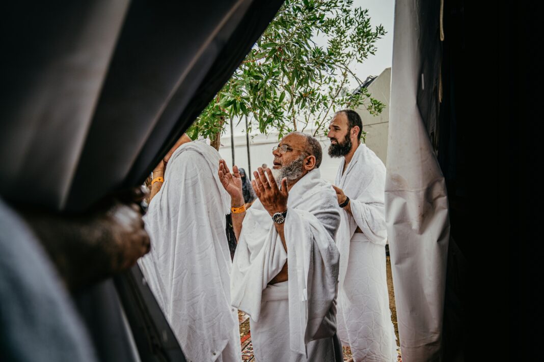 Grupa mężczyzn w białych szatach uczestniczy w duchowej modlitwie na świeżym powietrzu, nawiązując do tradycji kulturowych i religijnych.