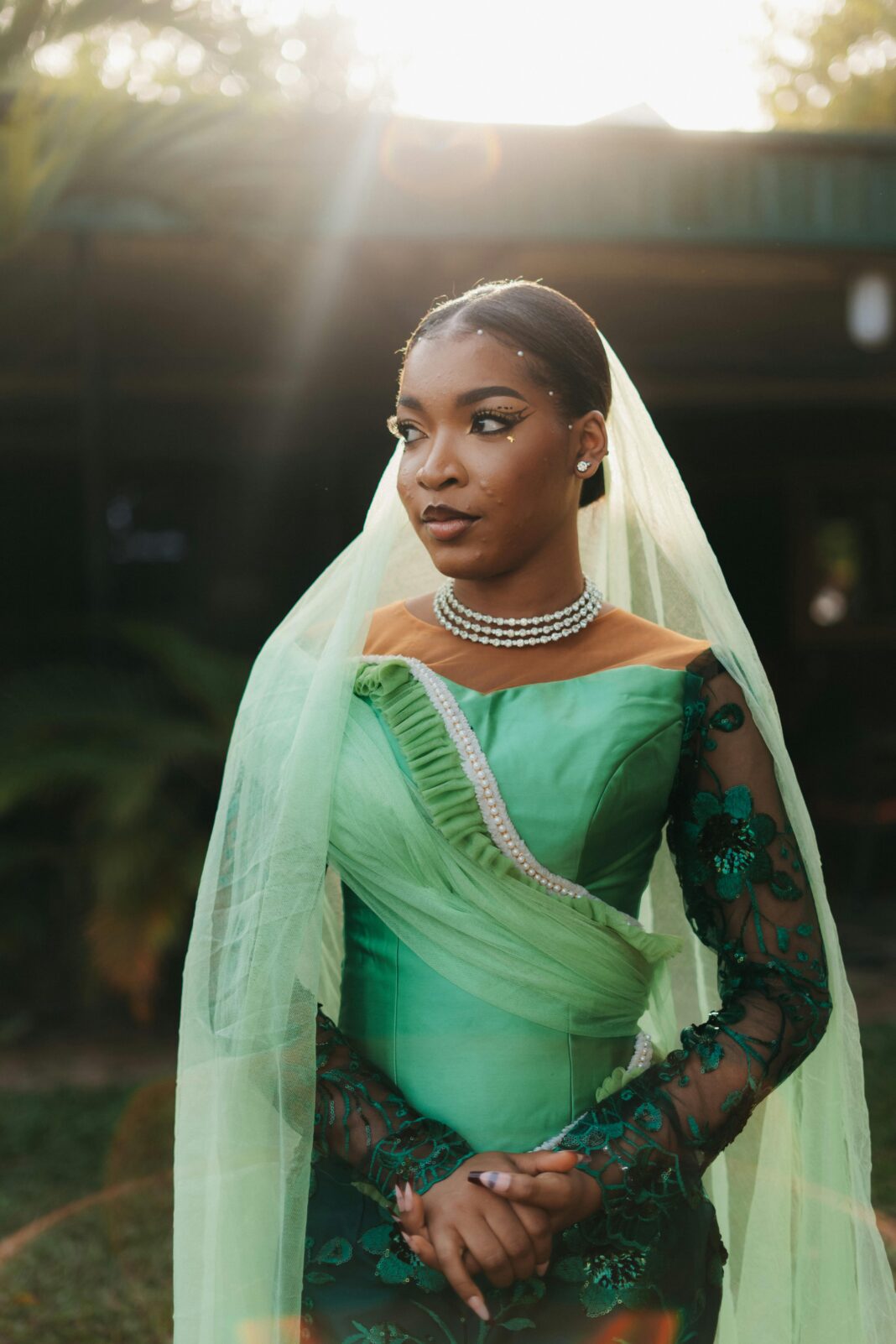 Urzekający portret afrykańskiej panny młodej w zielonej sukni z perłowymi dodatkami, uchwycony w świecącym naturalnym świetle.