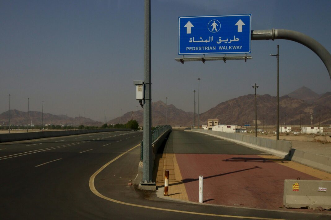 Droga ze znakiem chodnika dla pieszych, góry w tle w słoneczny dzień.