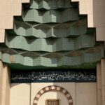 Skomplikowana fasada meczetu z wzorami geometrycznymi i kaligrafią arabską z tradycyjnymi islamskimi elementami.