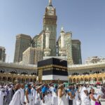 Duża grupa pielgrzymów gromadzi się w Kaaba w Mekce w Arabii Saudyjskiej podczas pielgrzymki hadżdż pod czystym, błękitnym niebem.