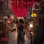 Kobieta spaceruje po tętniącym życiem targu antyków w Buenos Aires pod kolorowymi dekoracjami.