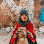 Argentyńska Ruta del Vino – Szlak Wina w Mendozie i San Juan Małe dziecko w ciepłym ubraniu pozuje z kozą na tle rustykalnego krajobrazu Jujuy w Argentynie.