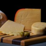 Wybór wyśmienitych serów, oliwek i rustykalnego chleba na drewnianej desce.