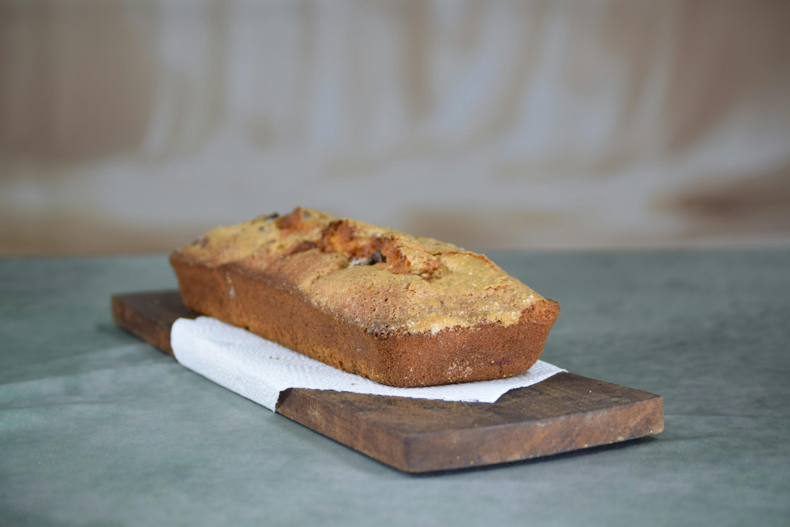 Domowy bochenek chleba bananowego na rustykalnej drewnianej desce, charakteryzujący się teksturą i ciepłem.