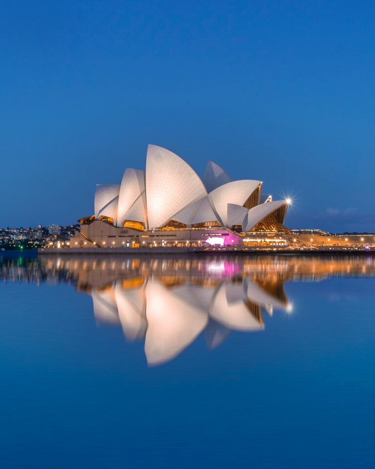 Piękny widok na Operę w Sydney i jej odbicie o zmierzchu, podkreślające kultową architekturę.