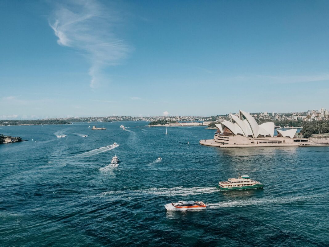 australia Widok z lotu ptaka na Operę w Sydney z łodziami w tętniącym życiem porcie w Sydney w ciągu dnia.