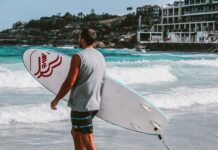 Noc na campingu w australijskim buszu Mężczyzna trzymający deskę surfingową na plaży Bondi w Sydney, gotowy do surfowania po tętniących życiem falach.