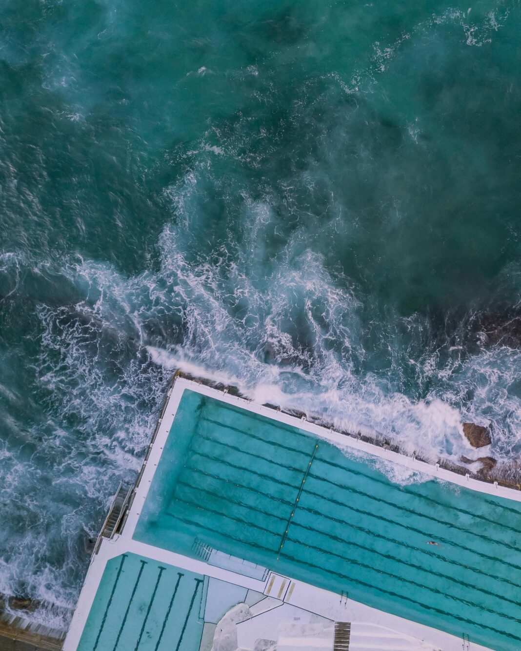 Zapierający dech w piersiach widok z lotu ptaka na słynny basen Bondi Beach spotykający się z falami oceanu w Australii.