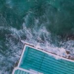 Zapierający dech w piersiach widok z lotu ptaka na słynny basen Bondi Beach spotykający się z falami oceanu w Australii.