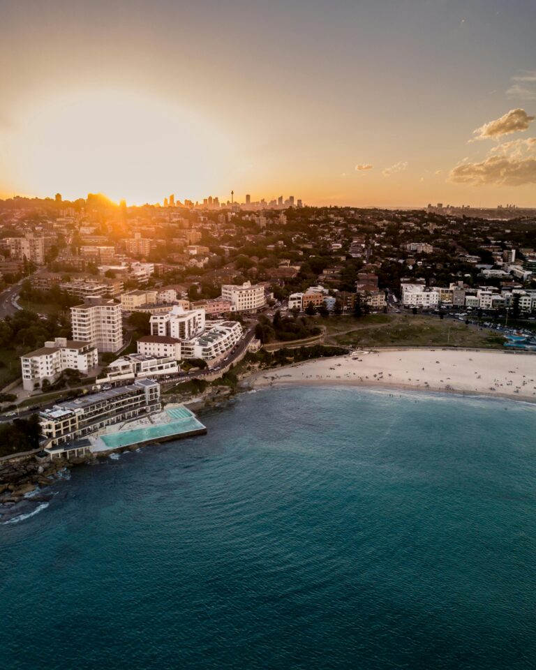 Oszałamiający widok z lotu ptaka na plażę Bondi w Sydney o zachodzie słońca, ukazujący wybrzeże i krajobraz miasta.