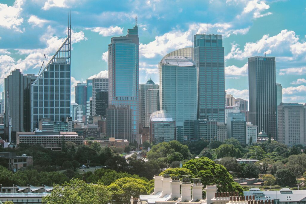 Widok z lotu ptaka na kultową panoramę Sydney z nowoczesnymi drapaczami chmur pod błękitnym niebem z chmurami.