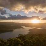 Jak wygląda lot helikopterem nad Sydney? Oszałamiająca panorama powietrzna tamy Hinze o zachodzie słońca, ukazująca spokojne odbicia wody i tętniące życiem niebo.