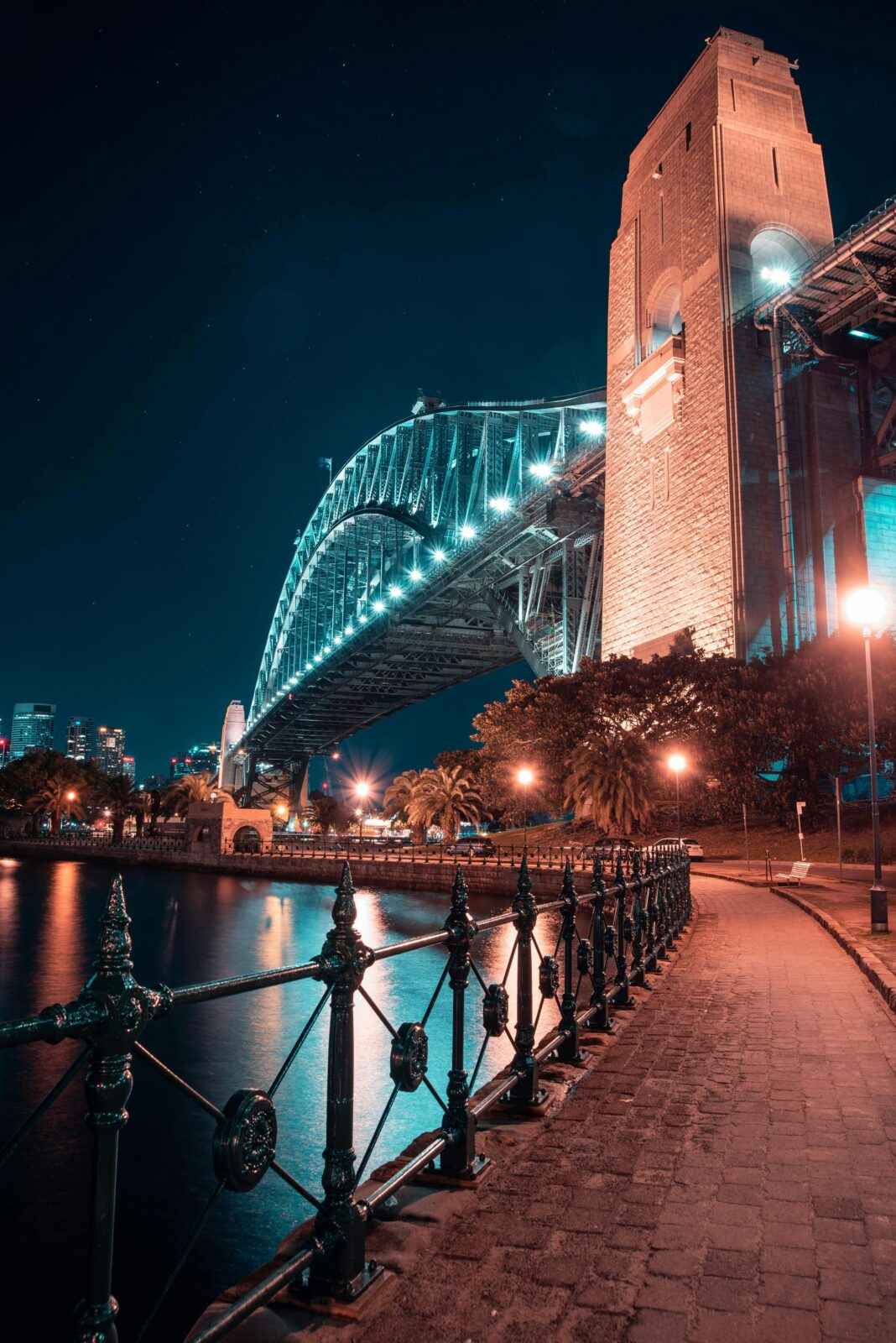 Oszałamiający nocny widok na Sydney Harbour Bridge ze świecącymi światłami i odbiciami wody.