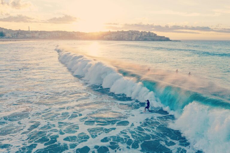 Surferzy pływają na falach na plaży Bondi podczas pięknego letniego zachodu słońca w Australii.