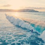 Surferzy pływają na falach na plaży Bondi podczas pięknego letniego zachodu słońca w Australii.