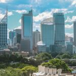 Widok z lotu ptaka na kultową panoramę Sydney z nowoczesnymi drapaczami chmur pod błękitnym niebem z chmurami.