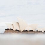 Rowerem po Australii – wyzwanie dla odważnych Mglisty widok na kultową Operę w Sydney w Australii, ukazujący jej charakterystyczną architekturę przypominającą żagiel.