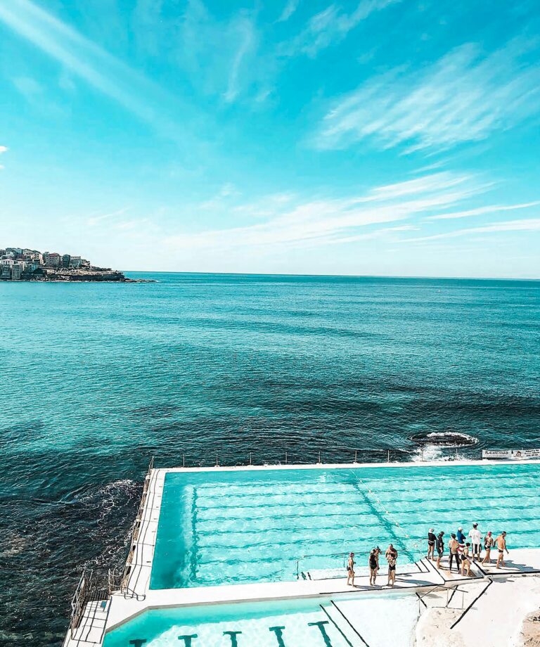 Zapierające dech w piersiach zdjęcie lotnicze kultowego basenu Bondi Beach z tętniącymi życiem turkusowymi wodami i czystym letnim niebem.