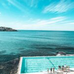 Zapierające dech w piersiach zdjęcie lotnicze kultowego basenu Bondi Beach z tętniącymi życiem turkusowymi wodami i czystym letnim niebem.