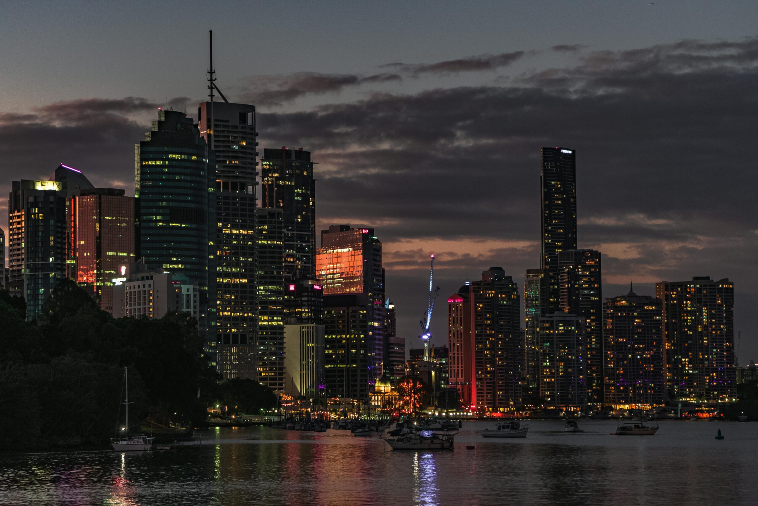 Urzekający widok na panoramę Brisbane o zachodzie słońca, odbijającą światła miasta na rzece.