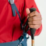 Zbliżenie na dłoń turysty trzymającego kijek trekkingowy, ubranego w sprzęt zimowy.