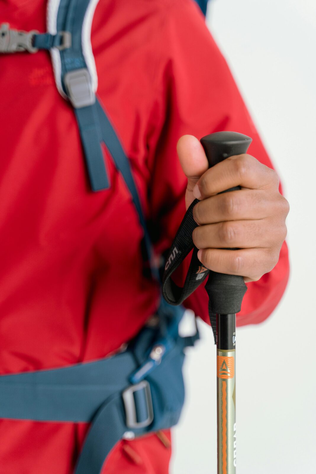 Zbliżenie na dłoń turysty trzymającego kijek trekkingowy, ubranego w sprzęt zimowy.