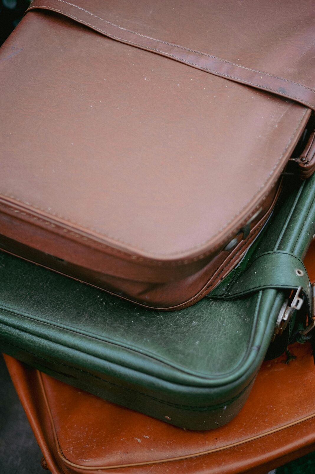 bagaz-podreczny Zbliżenie na stos starych skórzanych walizek w różnych kolorach, prezentujących ponadczasowy styl podróżowania.